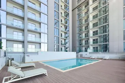 an apartment patio with a swimming pool and two tall buildings at GuestReady - Family retreat at Sobha Creek Vista in Dubai