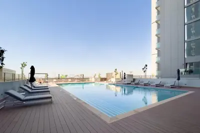 a woman sitting on a chair next to a swimming pool at GuestReady - Family retreat at Sobha Creek Vista in Dubai