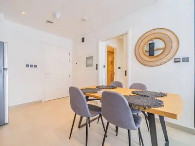 a dining room with a wooden table and chairs at Dubai Hills estate - 1Bedroom Apt in Dubai
