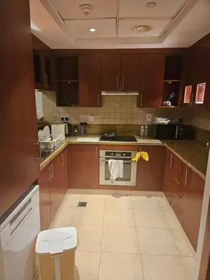 a kitchen with brown cabinets and a stove top oven at Fairways north in Dubai