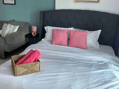a bed with pink pillows and a basket on it at Beautiful Studio Apartment in Dubai