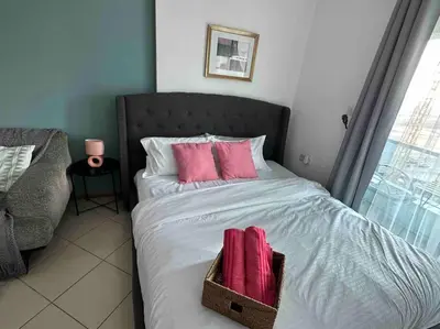 a bed with pink pillows and a basket on it at Beautiful Studio Apartment in Dubai