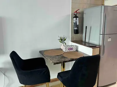 a kitchen with a table with two chairs and a refrigerator at Beautiful Studio Apartment in Dubai