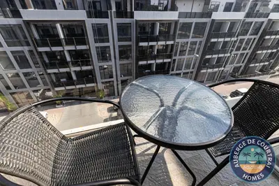 a table and chairs on a balcony with a building at Cozy Modern Studio Oxford Residence in Dubai