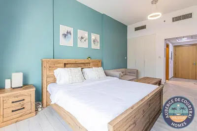 a bedroom with a bed and a blue wall at Cozy Modern Studio Oxford Residence in Dubai
