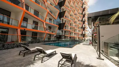 an apartment building with a swimming pool and chairs at Comfy 1br In Al Jaddaf Balcony Parking in Dubai