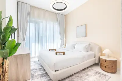 a white bedroom with a bed and a large window at Nicely Furnished Home in the Heart of Business Bay in Dubai