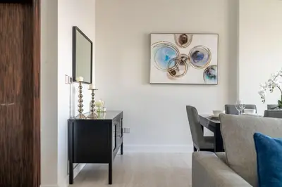 a living room with a table and a picture on the wall at GuestReady - Beachfront delight in JBR in Dubai