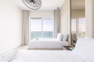 a bedroom with two beds and a large window at Luxury Coastal Escape - Bright 3BR Apt - La Vie JBR in Dubai