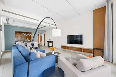 a living room with two blue couches and a kitchen at Spacious 1-Bedroom Apartment In Bay Square in Dubai