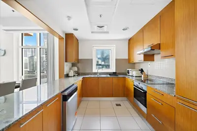 a kitchen with wooden cabinets and a large window at Spacious 1-Bedroom Apartment In Bay Square in Dubai