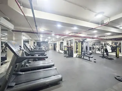 a gym with rows of treadmills and machines at Spacious 1-Bedroom Apartment In Bay Square in Dubai