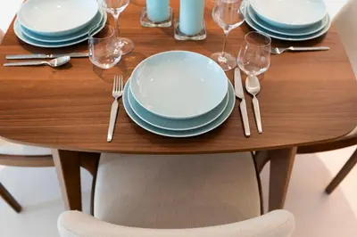 a wooden table with plates and wine glasses at Coastal Chic 1 Bedroom Apartment w private beach in Dubai