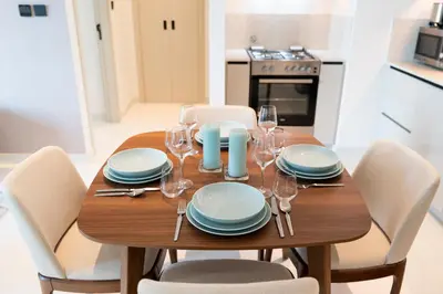 a dining room table with chairs and plates and wine glasses at Coastal Chic 1 Bedroom Apartment w private beach in Dubai
