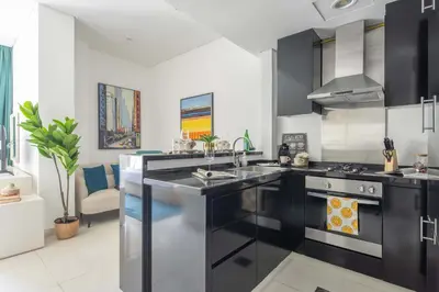a kitchen with black cabinets and a sink and a stove at Frank Porter - Damac Cour Jardin in Dubai