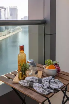 a wooden table with a bowl of fruit and a bottle at Frank Porter - Damac Cour Jardin in Dubai