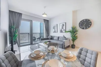 a living room with a table and chairs and a clock at Luxury 42-Floor 1BR flat in Harbour Views in Dubai