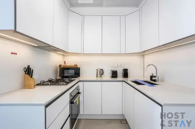 a white kitchen with white cabinets and appliances at Charming Studio in Luma 22, Jumeirah Village Circle in Dubai