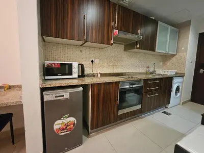 a kitchen with wooden cabinets and a microwave and a dishwasher at Stunning Apartment - High Floor - Canal View - Goldcrest Exectutive Tower in Dubai