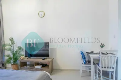 a room with a bed and a table and a sign at Bloomfields Stu In Carson in Dubai