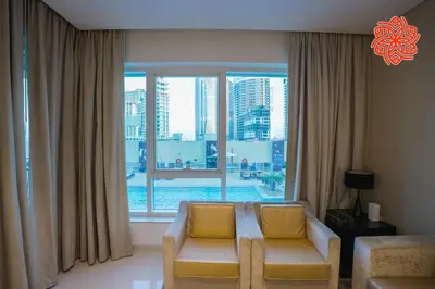 a living room with two chairs and a large window at Alashrafia Saray- Classy 1BDR apartment in Canal Views in Dubai