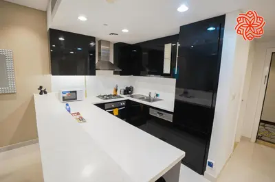 a kitchen with white counters and black cabinets at Alashrafia Saray- Classy 1BDR apartment in Canal Views in Dubai