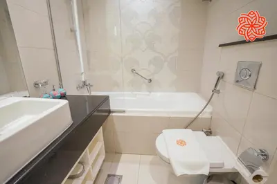 a bathroom with a tub and a toilet and a sink at Alashrafia Saray- Classy 1BDR apartment in Canal Views in Dubai
