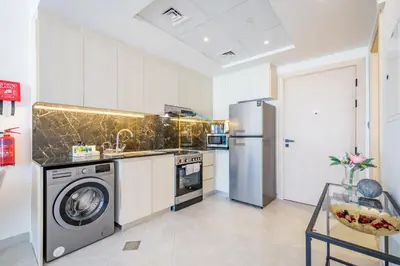 a kitchen with a washer and dryer and a refrigerator at Lovely 1BR in Binghatti Avenue Al Jaddaf by Deluxe Holiday Homes in Dubai