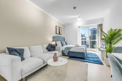 a white living room with a white couch and a bed at Waves - Charming Studio with Lake Views Close to Metro in Dubai