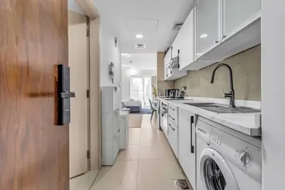 a kitchen with a sink and a washing machine at Waves - Charming Studio with Lake Views Close to Metro in Dubai