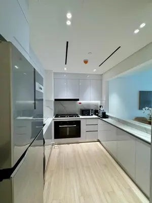 a kitchen with white cabinets and a wooden floor at Luxe 2br With Fast Wi-fi Parking, Gym And Pool! in Dubai