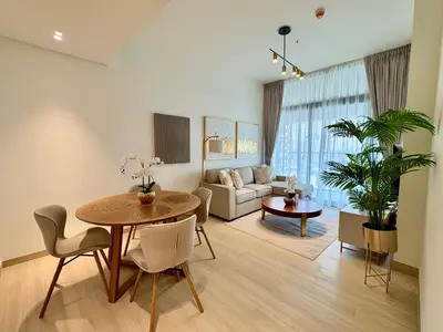 a living room with a table and a couch at Luxe 2br With Fast Wi-fi Parking, Gym And Pool! in Dubai