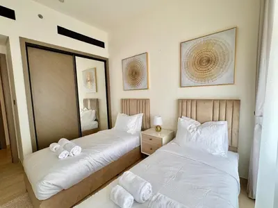 a bedroom with two beds and a mirror at Luxe 2br With Fast Wi-fi Parking, Gym And Pool! in Dubai