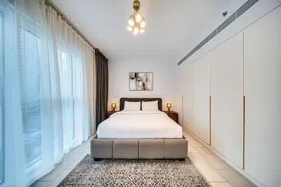 a bedroom with a bed and a large window at Lovely 1BD apartment in La Vie Dubai in Dubai