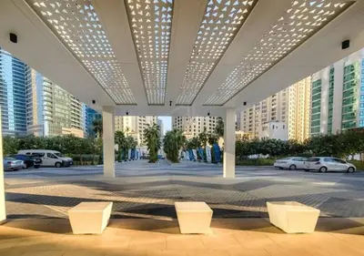 a pavilion with white chairs in a parking lot with buildings at Lovely 1BD apartment in La Vie Dubai in Dubai