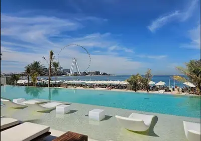 a swimming pool with white lounge chairs and the beach at Lovely 1BD apartment in La Vie Dubai in Dubai