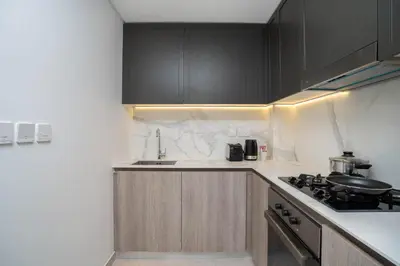 a kitchen with black cabinets and a stove top oven at Spacious and Modern Studio -Great Facilities in Dubai