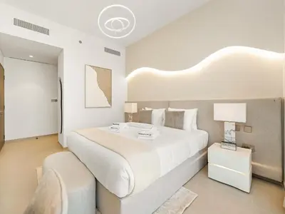 a large white bedroom with a large bed and a chair at SmartStay at Grande Signature - Burj Khalifa View - 5 min Dubai Mall - Downtown Dubai - Brand New Luxury Apartments in Dubai