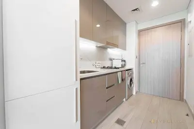 a kitchen with white cabinets and a washer at Everluxe Modern Pool View Studio In Al Jaddaf in Dubai