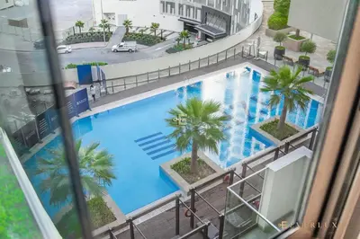 an overhead view of a large blue swimming pool with palm trees at Everluxe Modern Pool View Studio In Al Jaddaf in Dubai
