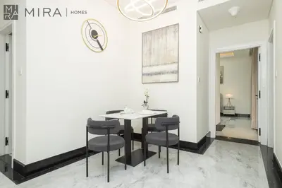 a dining room with white walls and a table and chairs at Mira Holiday Homes - Lovely new 1 bedroom in Downtown in Dubai