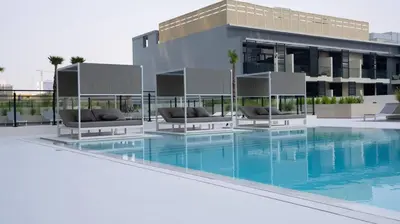 a swimming pool with chairs and a building at Furnished 1br In Jvc Pool Access Free Parking in Dubai