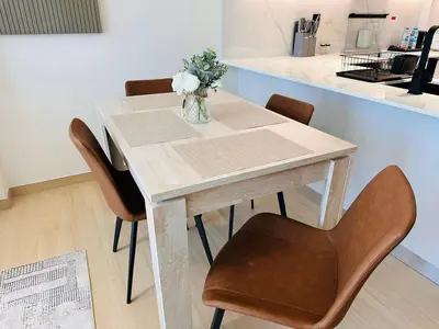 a table with chairs and a vase of flowers on it at Furnished 1br In Jvc Pool Access Free Parking in Dubai