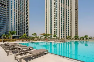 a large swimming pool with lounge chairs and buildings at Prime Location Full Burj View in Downtown Dubai in Dubai