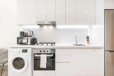a white kitchen with a washing machine and a sink at Exquisite Modern Home Minutes from Downtown Dubai in Dubai