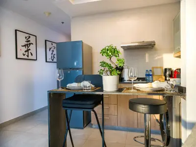 a kitchen with a blue refrigerator and two bar stools at EasyGo- Comfy STU in Dubai Marina -Zum04 in Dubai