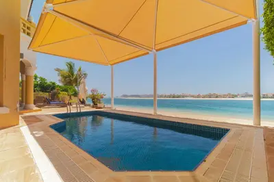 a swimming pool with an umbrella and the beach at Private Pool & Direct Beach Access-4BDR Villa in Dubai