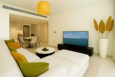 a living room with a white couch and a television at Pure Voyage Beachfront in Dubai