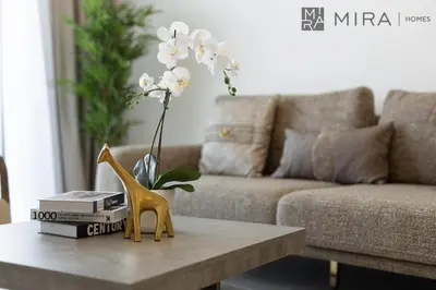 a table with a yellow chair and a vase of flowers at Mira Holiday Homes - Luxury and cosy 1 bedroom in JVC in Dubai