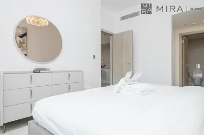 a white bedroom with a white dresser and a mirror at Mira Holiday Homes - Luxury and cosy 1 bedroom in JVC in Dubai